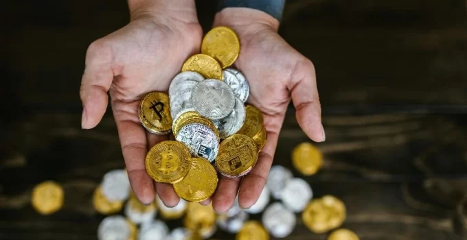 A person's hands holding a pile of various cryptocurrencies
