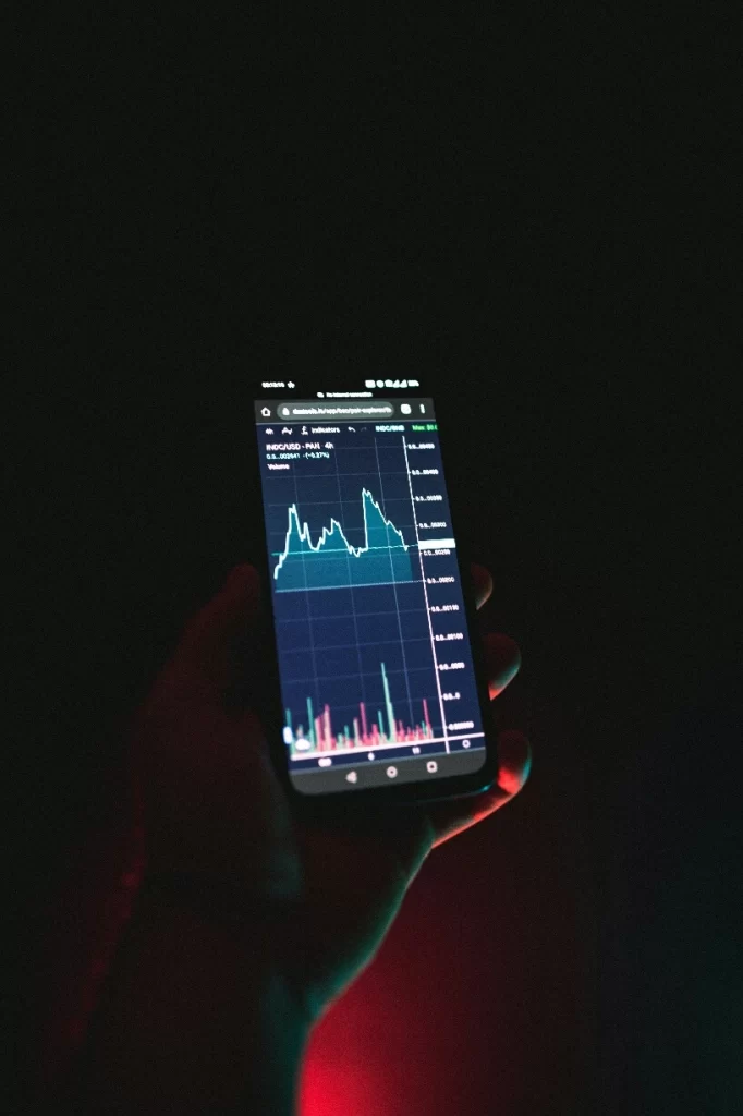 Smartphone screen showing a crypto trading chart with price swings and trading volume bars